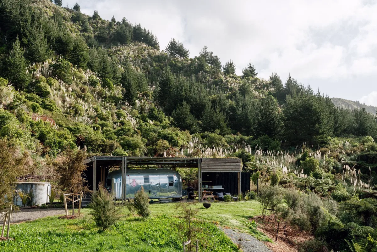 The Airstream below the toetoe-covered hillside